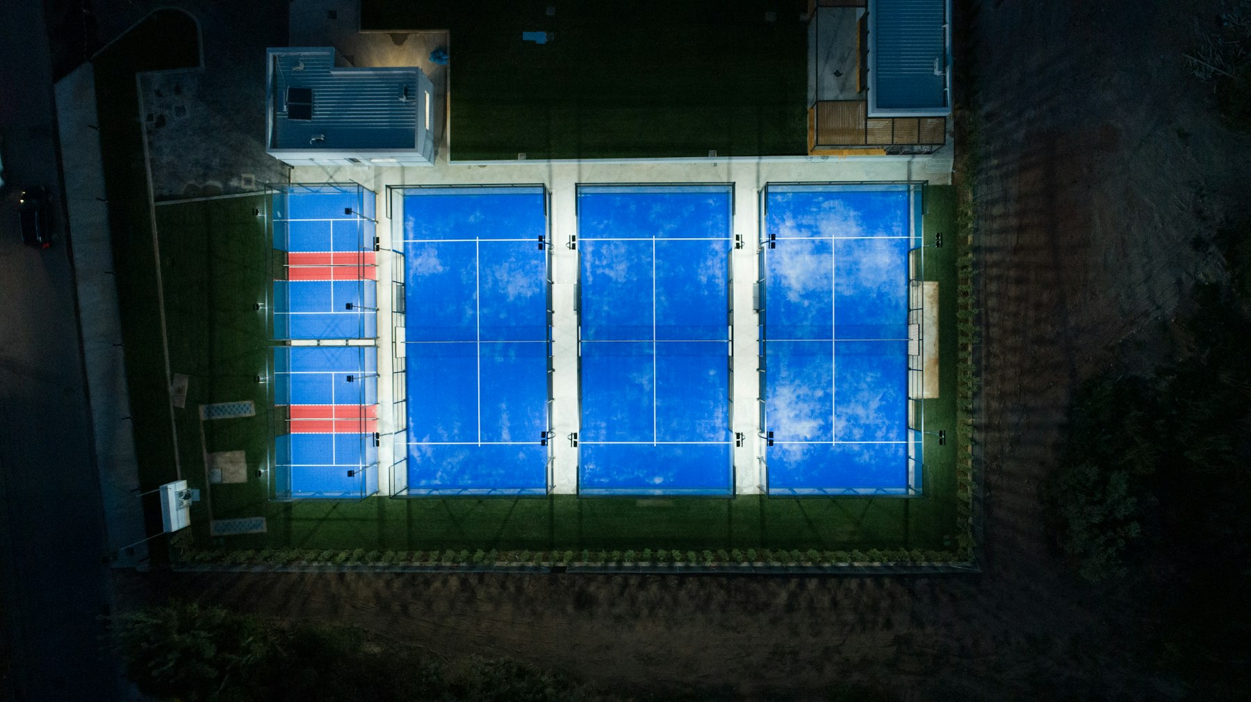 Aerial view of floodlit padel courts at night